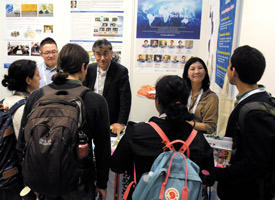Staff at the World Premier International Research Center Initiative (WPI) exhibition booth at the 2019 E-MRS Spring Meeting interacting with visitors.