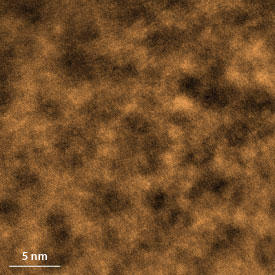 A scanning transmission electron microscopy image of a metallic glass shows that the structure contains cluster regions (dark areas in the micrograph) where atoms can still move after cooling to room temperature.